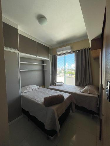 two beds in a room with a window at Apartamento Conforto/Praticidade in Manaus