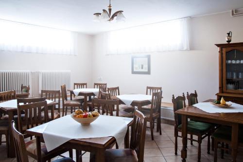 a dining room with tables and chairs and a bowl of fruit at Guest House Family in Kanjiža