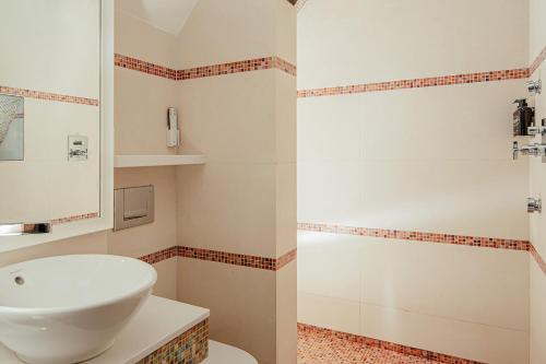 a white bathroom with a sink and a shower at Fanhams Hall, Exclusive Collection in Ware