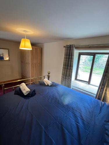 a bedroom with a large blue bed with a window at Stewards Bothy in Cornhill-on-tweed