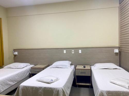a hospital room with two beds with white sheets at Hotel Rinkao in Cachoeiro de Itapemirim