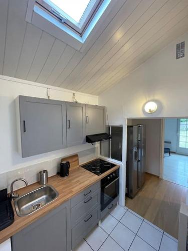 une cuisine avec un évier et une cuisinière dans l'établissement Maison paisible, élégante Aulnay-sous-Bois CDG JO, à Aulnay-sous-Bois