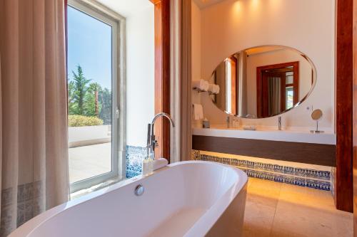a bath tub in a bathroom with a mirror at Palácio do Governador - Lisbon Hotel & Spa in Lisbon