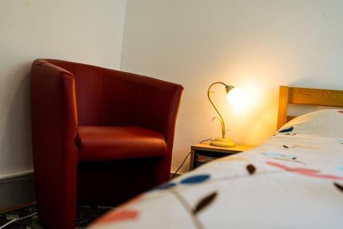 Un dormitorio con una silla roja al lado de una cama. en Appartement La Gare Viotte, en Besançon