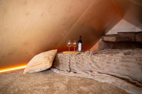 a bed with two wine glasses and wine bottles at Gold LUX in Kuldīga