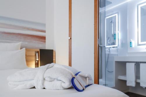 a pile of towels sitting on top of a bed at Novotel Luxembourg Centre in Luxembourg