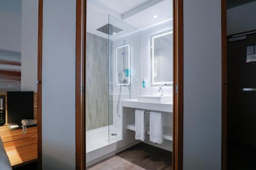 a bathroom with a sink and a mirror at Novotel Luxembourg Centre in Luxembourg