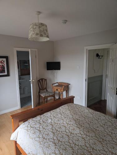 Un dormitorio con una cama, una mesa y una silla. en Clare House Bed & Breakfast, en Ballycastle