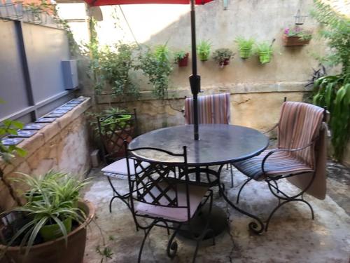 - une terrasse avec une table, 2 chaises et un parasol dans l'établissement la ruche des abeilles, à Avignon