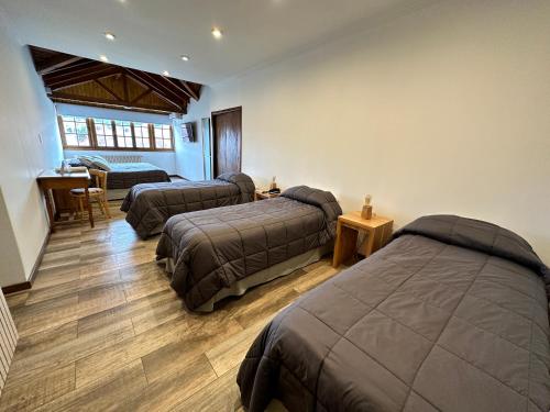 1 dormitorio con 3 camas, mesa y escritorio en Hostería Cumbres Blancas, en Esquel