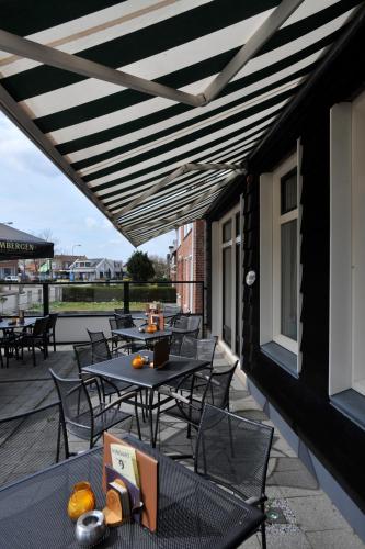 a patio with tables and chairs on a balcony at Bed & Breakfast d'Ouwe Smidse in Kamperland