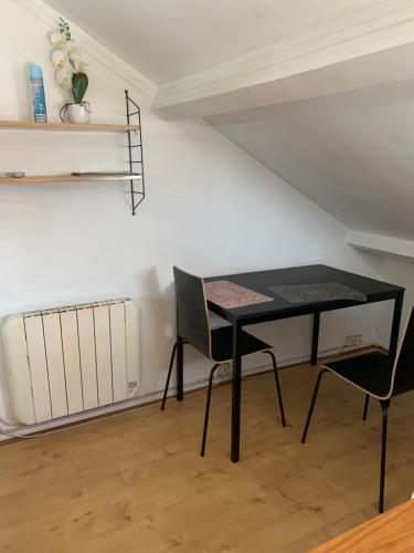 une table noire et deux chaises dans une pièce dans l'établissement Petit cocon centre ville, à Gagny