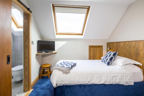 a bedroom with a bed and a bathroom with a window at The Dingle Pub Rooms in Dingle