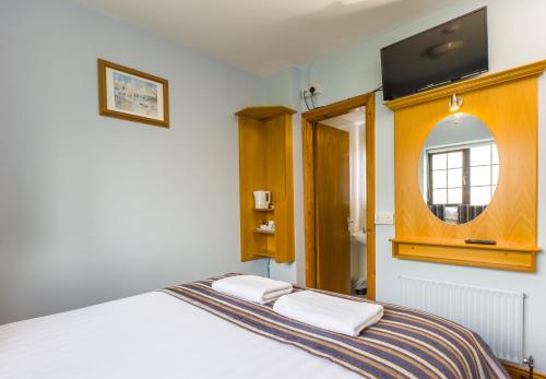a bedroom with a white bed with a mirror and a window at The Dingle Pub Rooms in Dingle