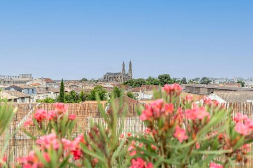 Vue sur une ville avec des fleurs roses au premier plan dans l'établissement Appartement Duplex Andréia - Welkeys, à Bordeaux
