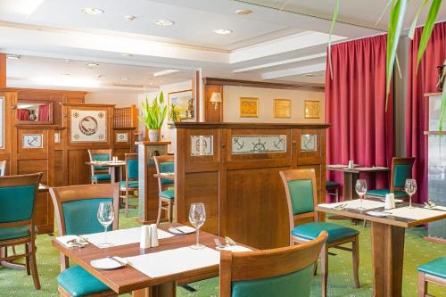 a restaurant with wooden tables and chairs and red curtains at SEETELHOTEL Nautic Usedom Hotel & Spa das Hotel für Wellness & Genuss auf Usedom in Ostseebad Koserow