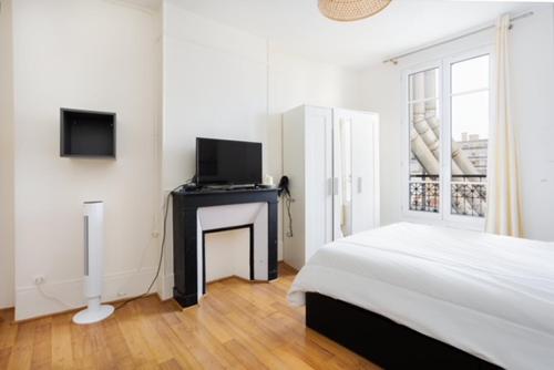 une chambre blanche avec un lit et une télévision dans l'établissement Appartement Grenelle, à Paris