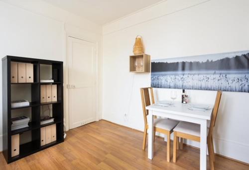 une salle à manger avec une table et des chaises blanches dans l'établissement Appartement Grenelle, à Paris