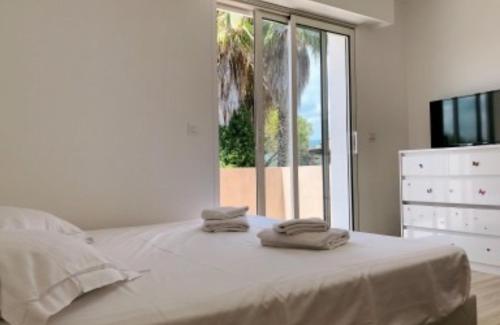 une chambre blanche avec un lit avec deux serviettes dessus dans l'établissement Villa Panorama, à Cagnes-sur-Mer