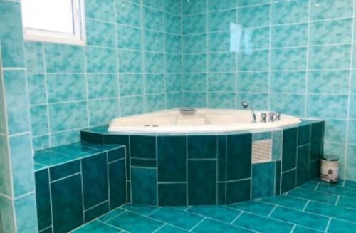La salle de bains est pourvue de carrelage bleu, d'une baignoire et d'un lavabo. dans l'établissement Villa Panorama, à Cagnes-sur-Mer