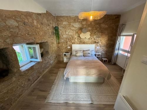 a bedroom with a bed and a stone wall at Casadeira de Mucha in Camariñas