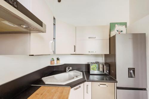 - une cuisine avec un évier et des placards blancs dans l'établissement MONT FLEURI- Somptueux 2 pièces - Parking - Menton, à Menton