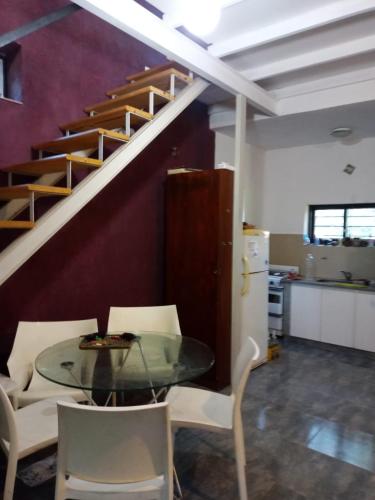a dining room with a glass table and stairs at Casa en Villa Los Aromos cerca del río in Villa Los Aromos