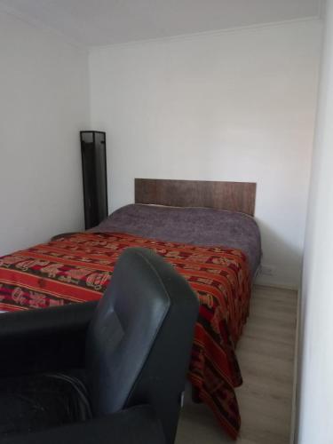 a bedroom with a bed with a chair next to it at Casa en Villa Los Aromos cerca del río in Villa Los Aromos