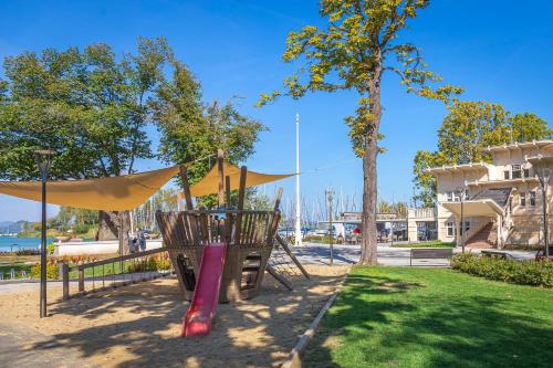 a park with a playground with a swing at Aranyhíd Apartman in Balatonföldvár