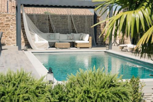 Una piscina con un sofá y una hamaca al lado de una casa. en Maison privée provençale, en Rochefort-du-Gard