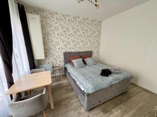 a bedroom with a bed and a table with a chair at Appartement Romantique - 044 in Rouen