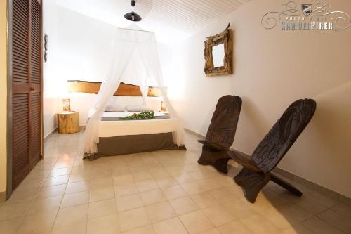 a bedroom with a bed and two chairs at Orcéa & Spa Séjours Ecofriendly in Sainte-Anne
