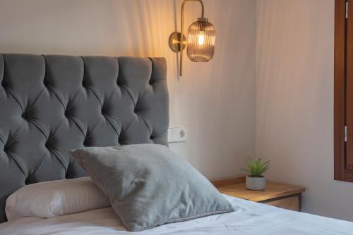 a bed with a gray padded headboard and a pillow at La Granja Villa in La Granja de San Ildefonso
