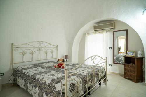 - un ours en peluche assis sur un lit dans une chambre dans l'établissement Trullo Tre Coni, à Cisternino