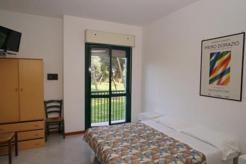 モンテジルヴァーノにあるResidence Club le Nazioniのベッドルーム1室(ベッド1台付)、スライド式ガラスドアが備わります。