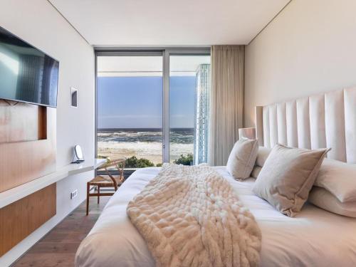 a bedroom with a large bed with a view of the ocean at Beachfront Bliss in Cape Town