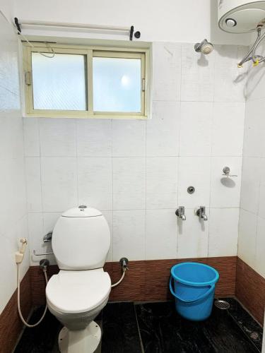 a bathroom with a toilet and a blue bucket at Earth songs by Green leaves - 10 kms from kotagiri in Kotagiri