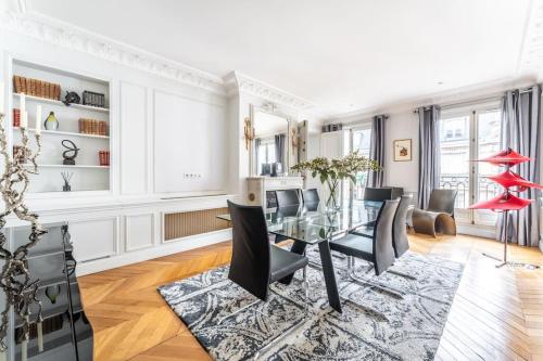 une salle à manger avec une table en verre et des chaises noires dans l'établissement Luxueux Appartment Georges V, à Paris