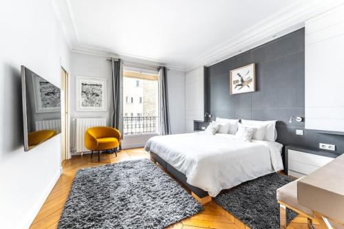 une chambre avec un grand lit blanc et une chaise jaune dans l'établissement Luxueux Appartment Georges V, à Paris