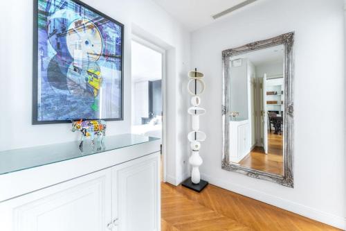 La salle de bains est pourvue d'un miroir et d'un mur blanc. dans l'établissement Luxueux Appartment Georges V, à Paris