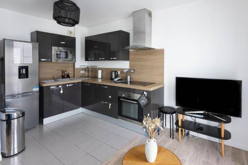 a kitchen with black cabinets and a flat screen tv at Le VAL HOME - 20min de PARIS et ORLY - Balcon - WIFI - Espace de travail in Valenton