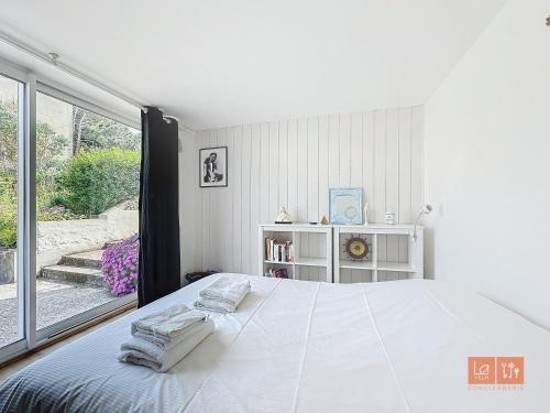 a white bedroom with a large bed and a window at Le Clos - Proximité plage in Ambleteuse
