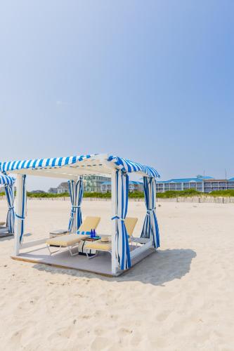 a gazebo on the beach with two chairs and aermottermottermott at La Mer Beachfront Resort in Cape May