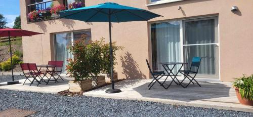 a table and chairs with an umbrella in front of a building at Les chambres de la fontaine de brul in Sainte-Ode