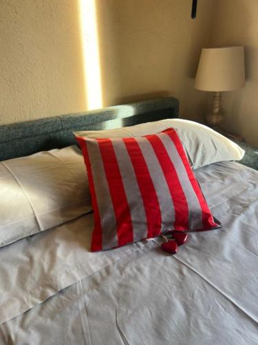 a bed with a red and white striped pillow on it at Ninette, intimità e natura in Sauze di Cesana