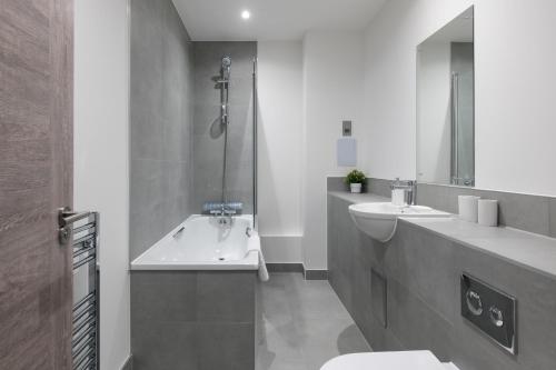 布莱奇利Modern Flat with Parking - Last Min Deals Available的带两个水槽、一个浴缸和一个马桶的浴室