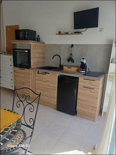 a kitchen with wooden cabinets and a stove top oven at Studio mi casa es su casa in Vauvert