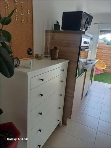 a kitchen with a white dresser with a microwave at Studio mi casa es su casa in Vauvert