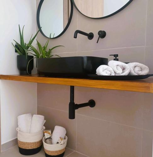 a bathroom with a black sink and towels on a shelf at nisaki rooms & apartments in Methana