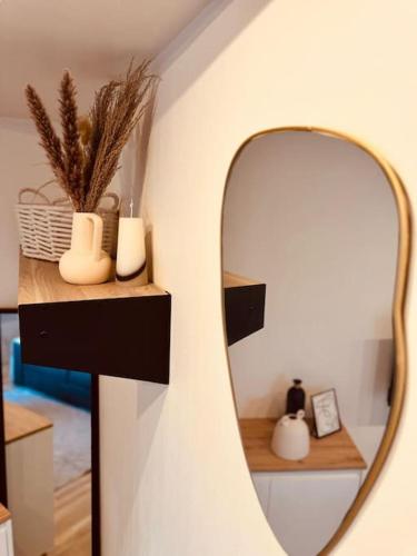 un miroir sur un mur avec des vases sur une étagère dans l'établissement Le Cosy Du Roi, WIFI,GARE,PARIS, à Versailles